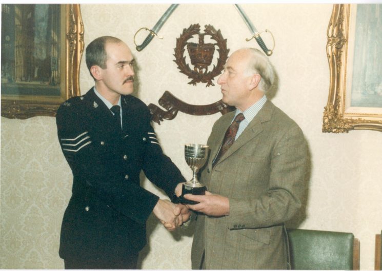 Police Sergeant A. Grimmett being presented with the Colburn Trophy for prize-winning essay on 'Police in Public Disorder', by Mr Oscar Colburn  Commander British Empire; Justice of the Peace; Deputy Lieutenant 1984. (Gloucestershire Police Archives URN 388) 